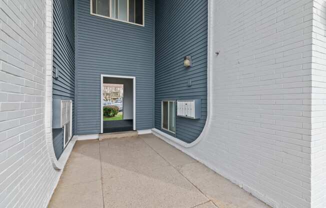 a long hallway with a door to a building with blue and white walls