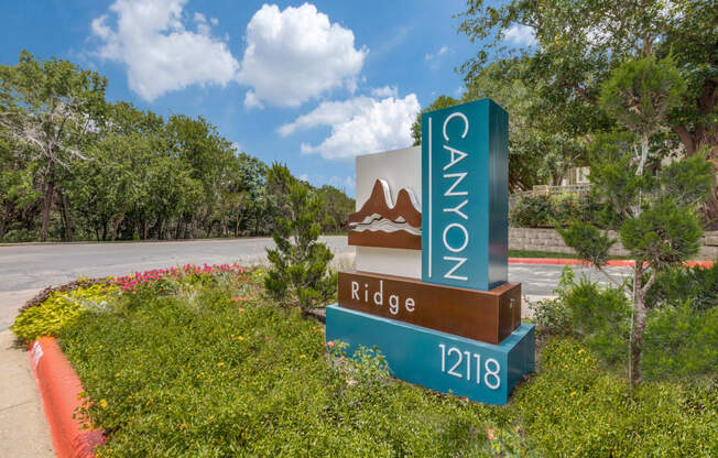 A sign for Canyon Ridge 12118 is in front of a green hedge.