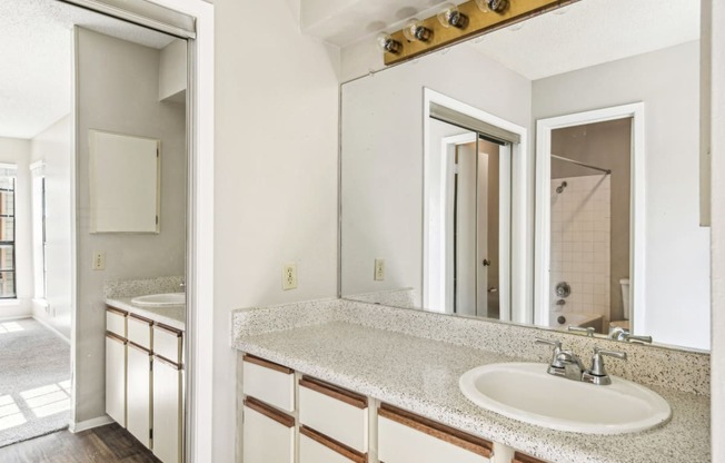 Spacious bathroom with a big mirror and two vanities separated by a wall at Bandera Crossing apartments in San Antonio, TX