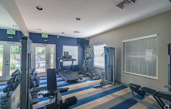 a gym with weights and cardio machines and a window