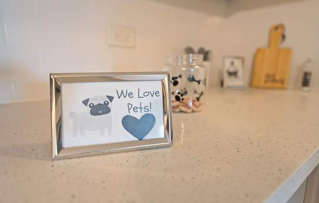 A picture frame with a dog and a heart and the words "We Love Pets!" on it.