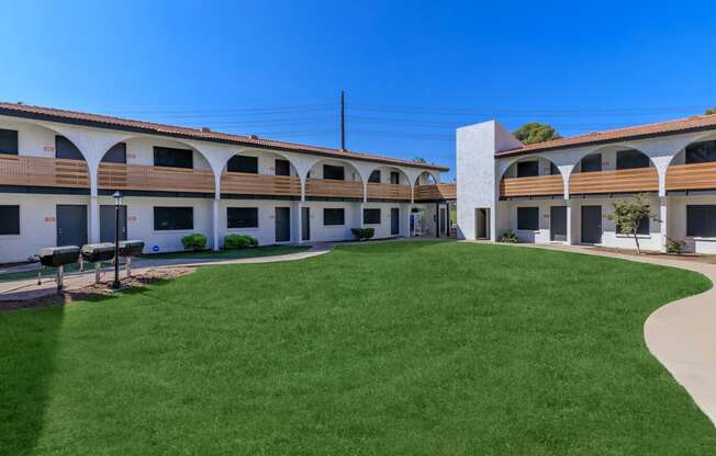 a courtyard with a grassy area and a building in the background