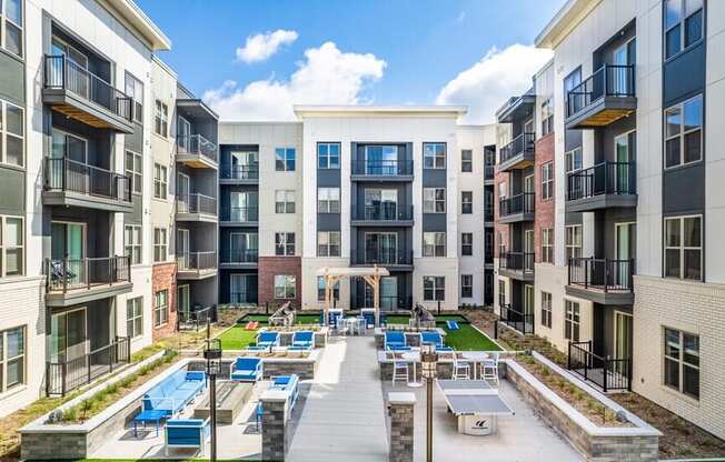 A sunny day at a modern apartment complex with a pool and lounge chairs.