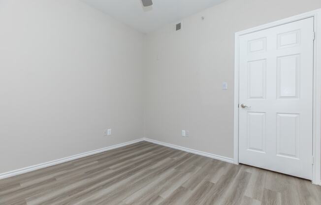 a bedroom with hardwood floors and a white door