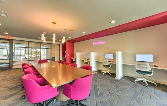 a conference room with a wooden table and pink chairs  at Pinnacle Apartments, Jacksonville, Florida