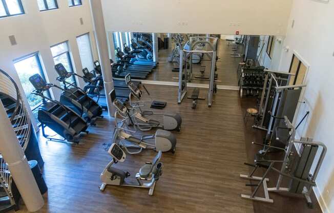 a gym with cardio machines and weights on a wood floor