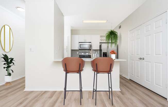 a living room with two stools in front of a kitchen