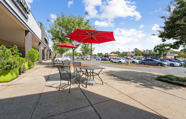 A red umbrella is on a table outside a building.