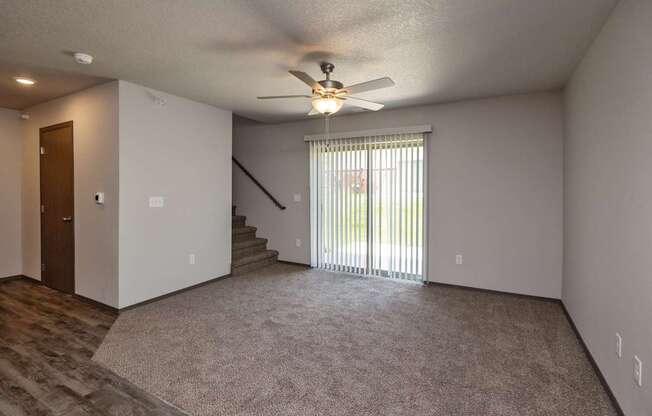 A room with a ceiling fan and a carpeted floor.