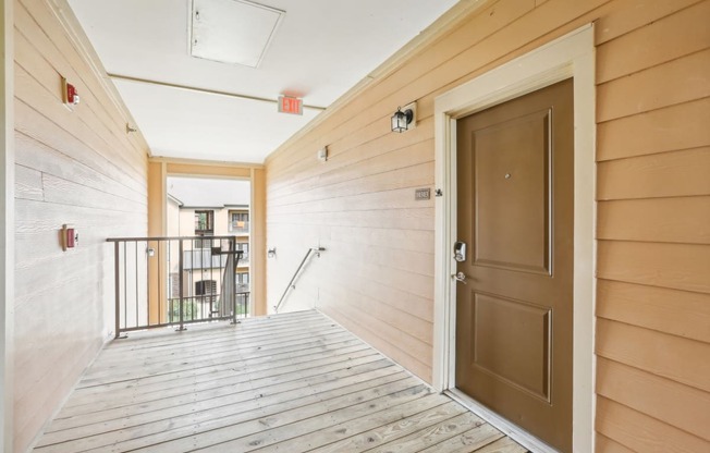 the entrance to a condo with a wooden floor and a brown door