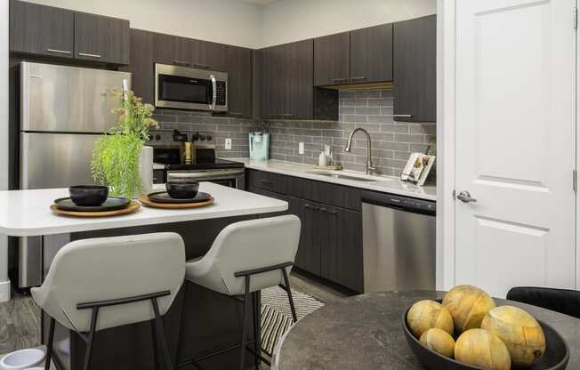 a kitchen with stainless steel appliances and an island with chairs