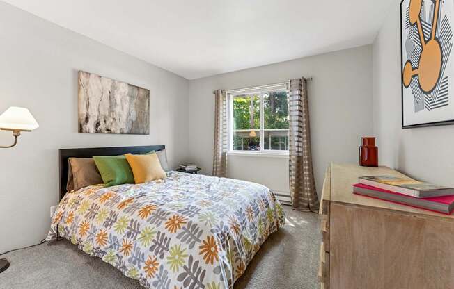 A bedroom with a bed, nightstand, and a painting on the wall.