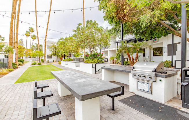 a patio with a barbecue grill and a table with benches