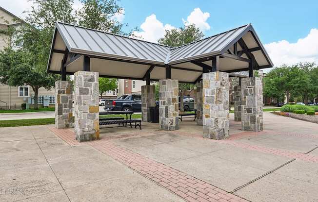 A covered walkway with a metal roof and stone pillars.