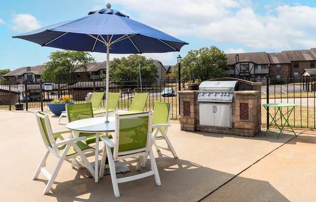 a patio with a table and chairs with an umbrella and a grill