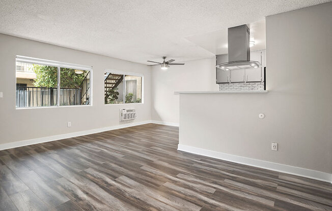 Large hardwood floored living room with ceiling fan over dining room.