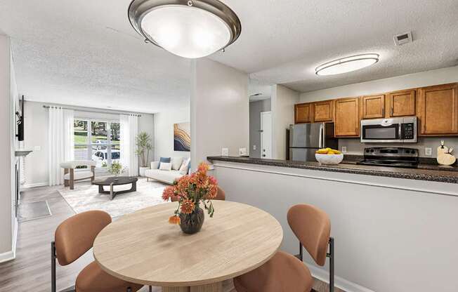 A kitchen with a table and chairs in the foreground and a living room in the background.