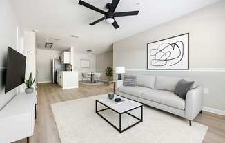 A living room with a white couch, a coffee table, and a ceiling fan.