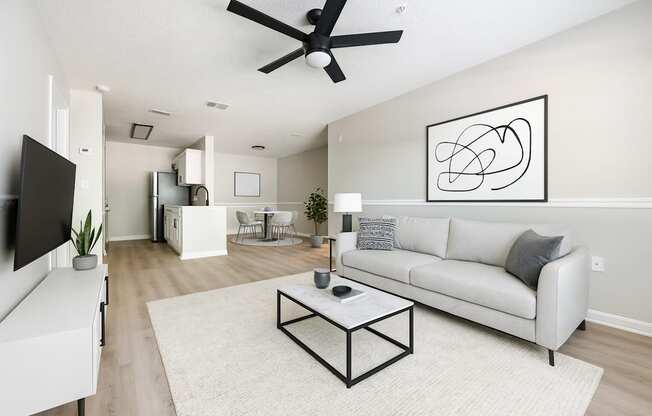 A living room with a white couch, a coffee table, and a ceiling fan.