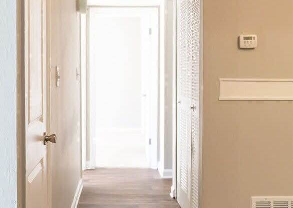 A long hallway with a door on the left and a window on the right.