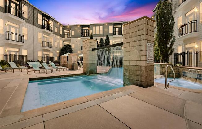 a swimming pool with a fountain in front of an apartment building