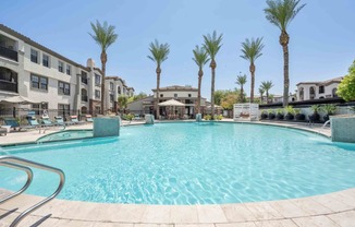Resort-style pool with blue skies, palm trees and the Zone Luxe apartments in Glendale, AZ in the backdrop.