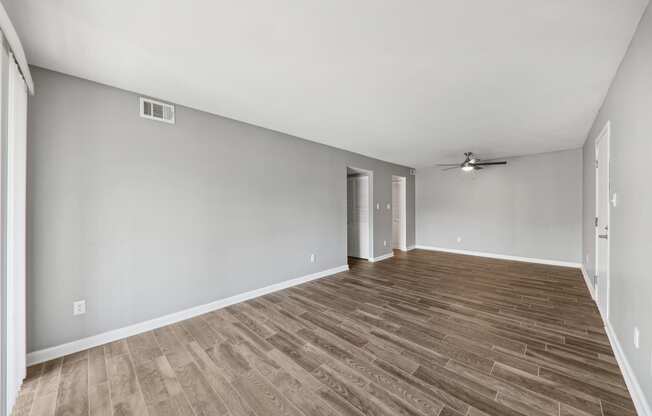 an empty living room with wood flooring and a ceiling fan