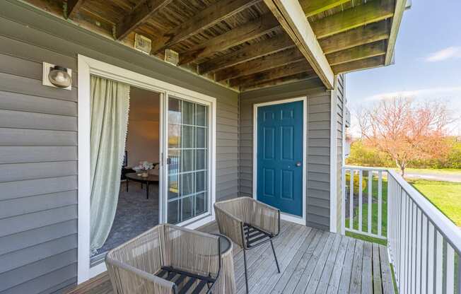 a covered porch with two chairs and a blue door