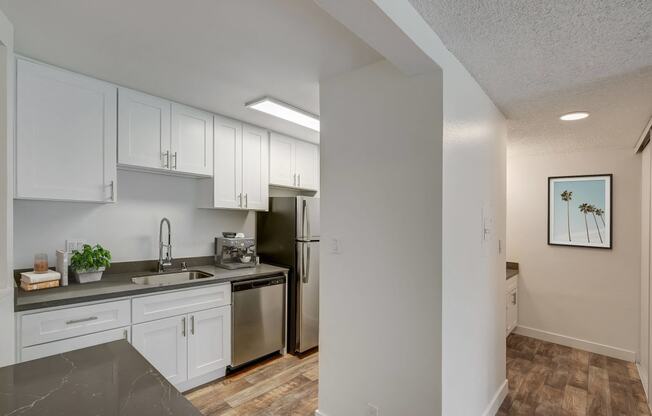 an empty kitchen with white cabinets and a stainless steel refrigerator