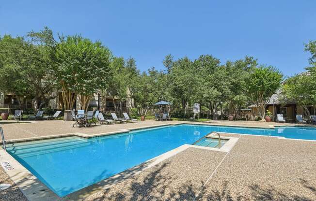 a swimming pool with chairs and trees around it