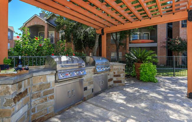 two stainless steel barbecues under a pergola