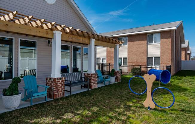 A dog bone sculpture is in the front yard of a house with a wooden pergola.
