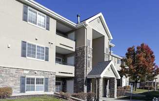 an exterior view of an apartment building with a lawn and trees