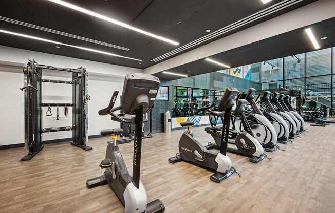 A gym with a variety of exercise equipment including treadmills, stationary bikes, and weight machines.