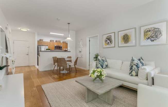 A living room with a white couch, a grey coffee table, and a dining table with chairs.