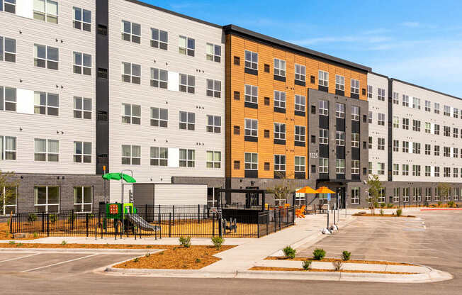 A modern apartment complex with a playground in front.