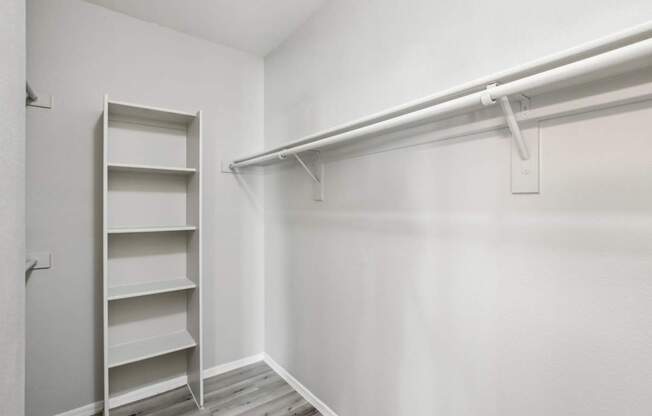 A white closet with a shelf and a white door.