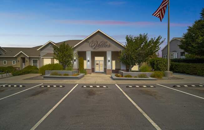 an empty parking lot in front of a building with an flag