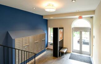 a hallway with blue walls and a staircase with a chair and lockers