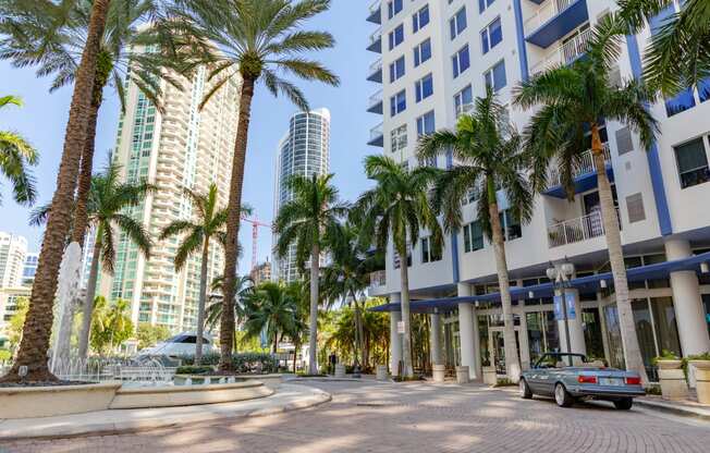 a city street with palm trees and tall buildings
