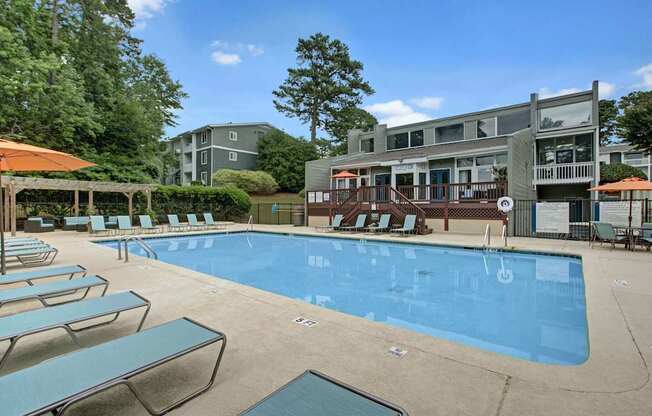 A large swimming pool surrounded by lounge chairs and umbrellas.