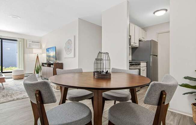 A modern dining room with a round table and grey chairs.