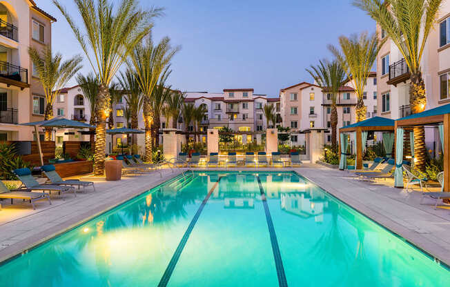 A large swimming pool surrounded by palm trees and lounge chairs.