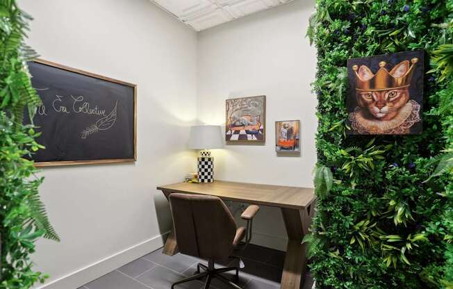 A room with a desk, chair, and a green plant wall.