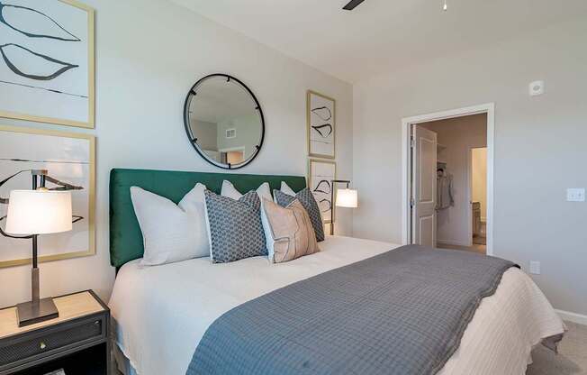 1-Bedroom Apartments in Madison, AL - Paxton Place - Spacious Bedroom with Plush Carpet, Bed, Nightstands with Lamps, Mirror, and Spacious Closet.