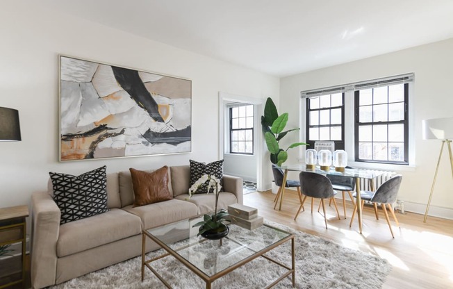 living area with large windows, sofa, coffee table, hardwood floors and view of dining area at the dahlia apartments in washington dc