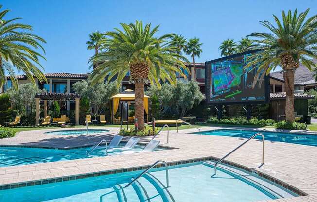 A pool surrounded by palm trees and lounge chairs.