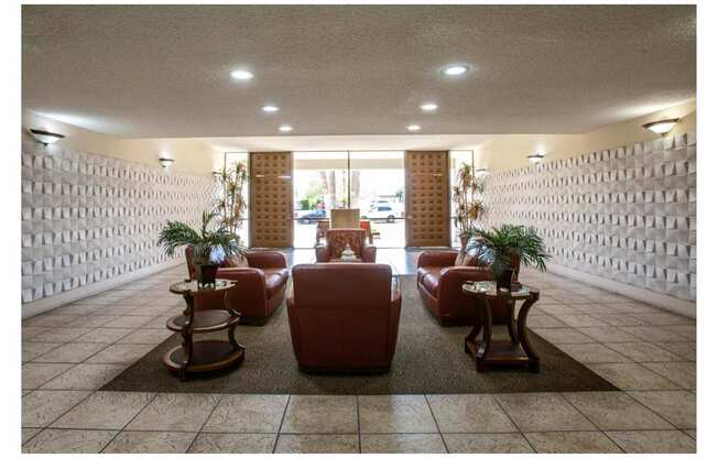 A waiting area with red chairs and a plant on a table.