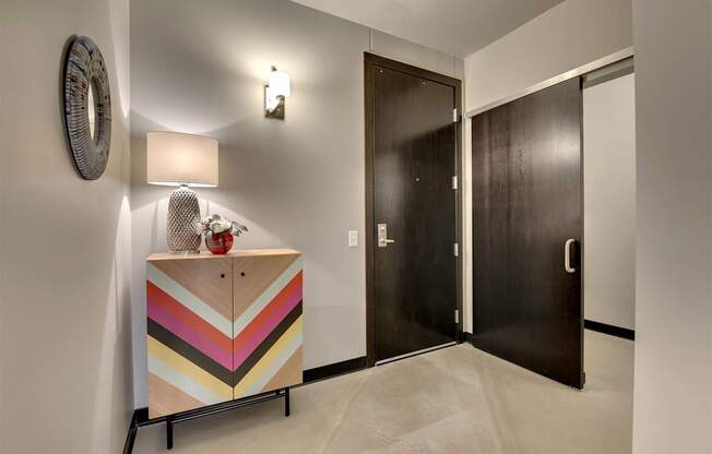A wooden cabinet with a chevron pattern painted in pastel colors sits in a hallway.