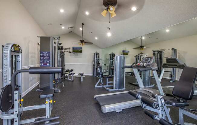 A gym with a variety of equipment including a treadmill, weights, and a bench press.